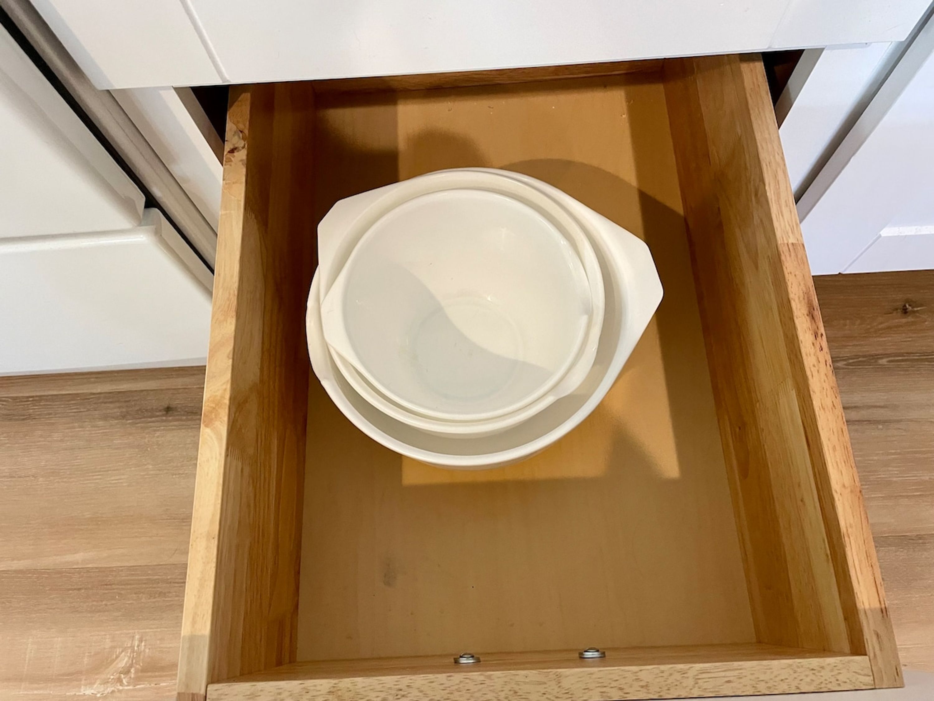 A wooden drawer with a white plastic container inside.