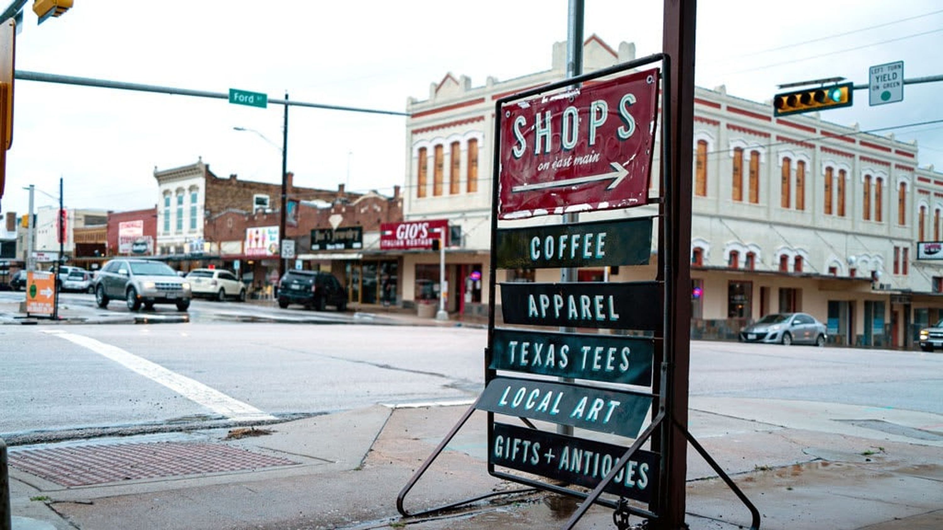 Straßenansicht mit einem Schild, das lokale Geschäfte wie Kaffee, Bekleidung, Texas-Tees, Kunsthandwerk und Antiquitäten/Geschenkartikel auflistet.