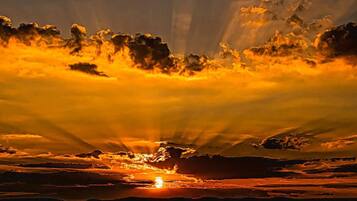A sunset with rays of sunlight piercing through clouds.