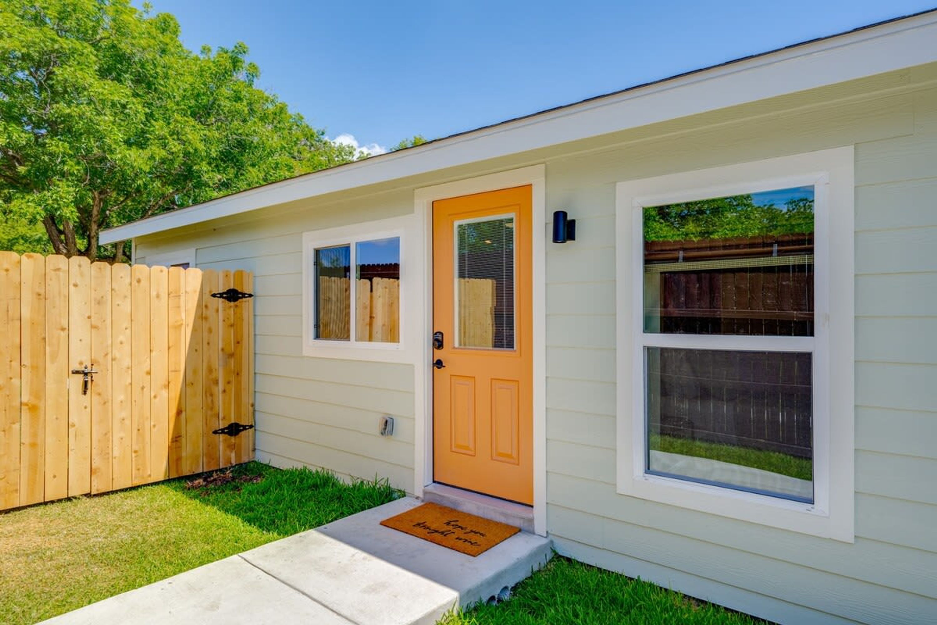 A single-story house with a front door, a small porch, and a wooden fence.