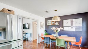 A modern kitchen with stainless steel appliances, a dining area with a wooden table and colorful chairs, and a dark accent wall with framed artwork. - 8b 4b Nearby Pool Blanco Wine Trail Town sq (Blanco)