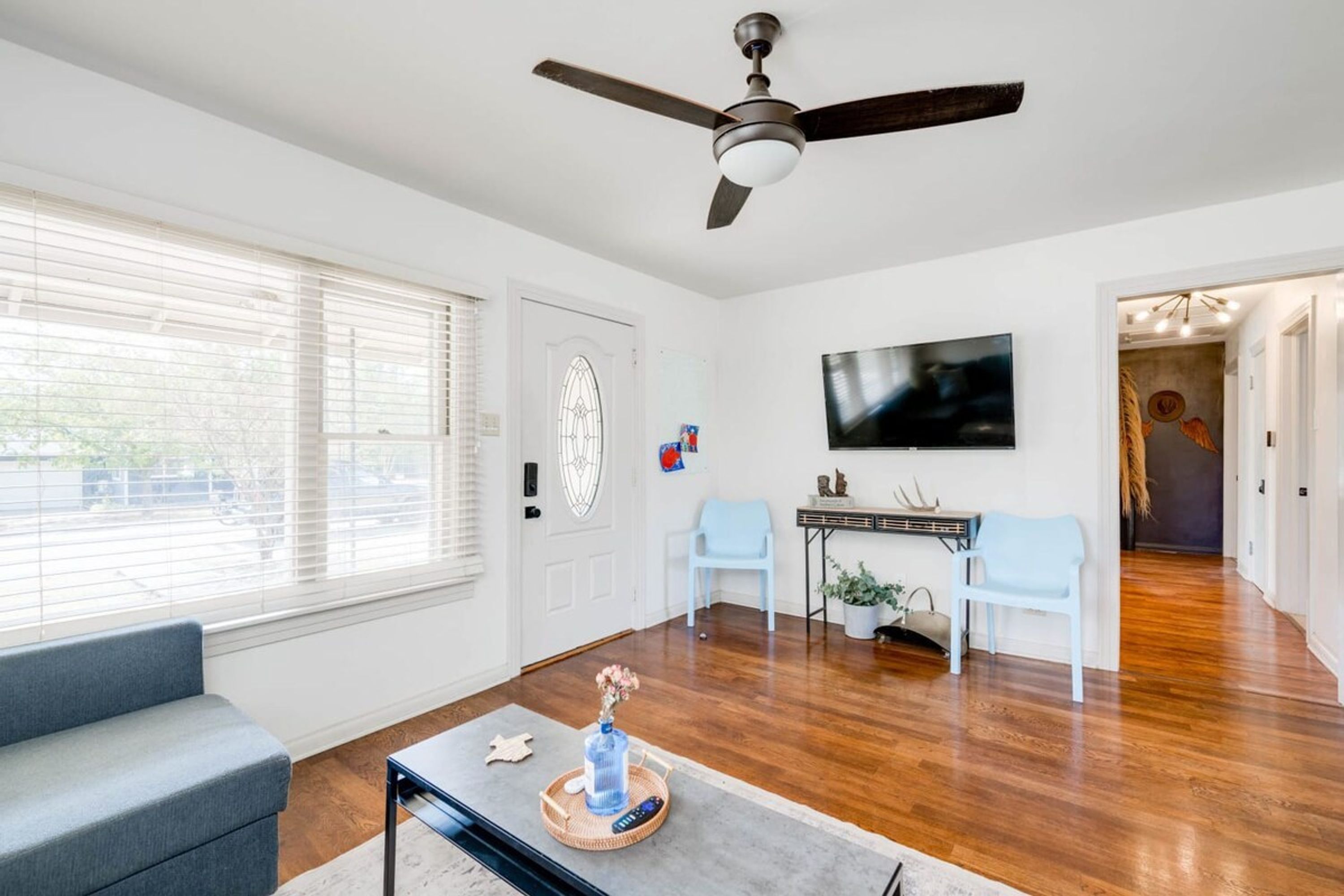 A living room with a ceiling fan, a television, a sofa, and a coffee table with decorative items.