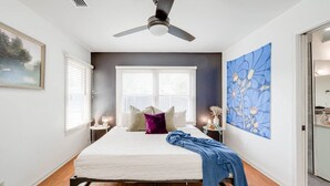 A bedroom with a bed, a ceiling fan, two windows with blinds, a painting on the wall, and a nightstand with a lamp. - 8b 4b Nearby Pool Blanco Wine Trail Town sq (Blanco)