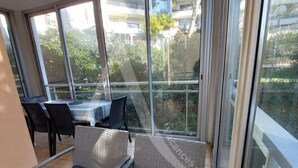 Ein sonniger Balkon mit Korbmöbeln und Blick auf Grünflächen und Gebäude.