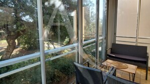 Ein Balkon mit Blick auf Bäume, einer Korbsessel-Sofa und einem kleinen Tisch.