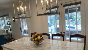 Una cocina con encimera de mármol, frutero y candelabro.