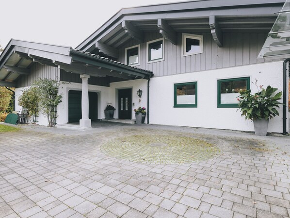 A building with a covered entrance, a paved courtyard, and potted plants.
