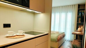 Una cucina compatta con un forno a microonde, un lavandino e due tazze bianche su un tappetino.