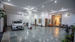 A spacious lobby with a white car parked in the center, potted plants, and a staircase leading to another area. - Hotel Haridas Haveli Udaipur (Udaipur)