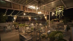 An outdoor patio area with tables and chairs, string lights, and potted plants. - Hotel Haridas Haveli Udaipur (Udaipur)
