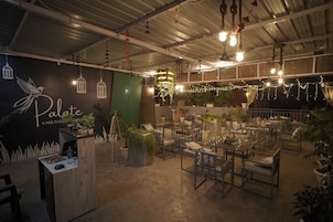 Un restaurante con una decoración rústica, con bombillas colgantes, luces de cadena y plantas en macetas.