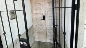 Una entrada tancada amb una porta de fusta i una reixa metàl·lica.