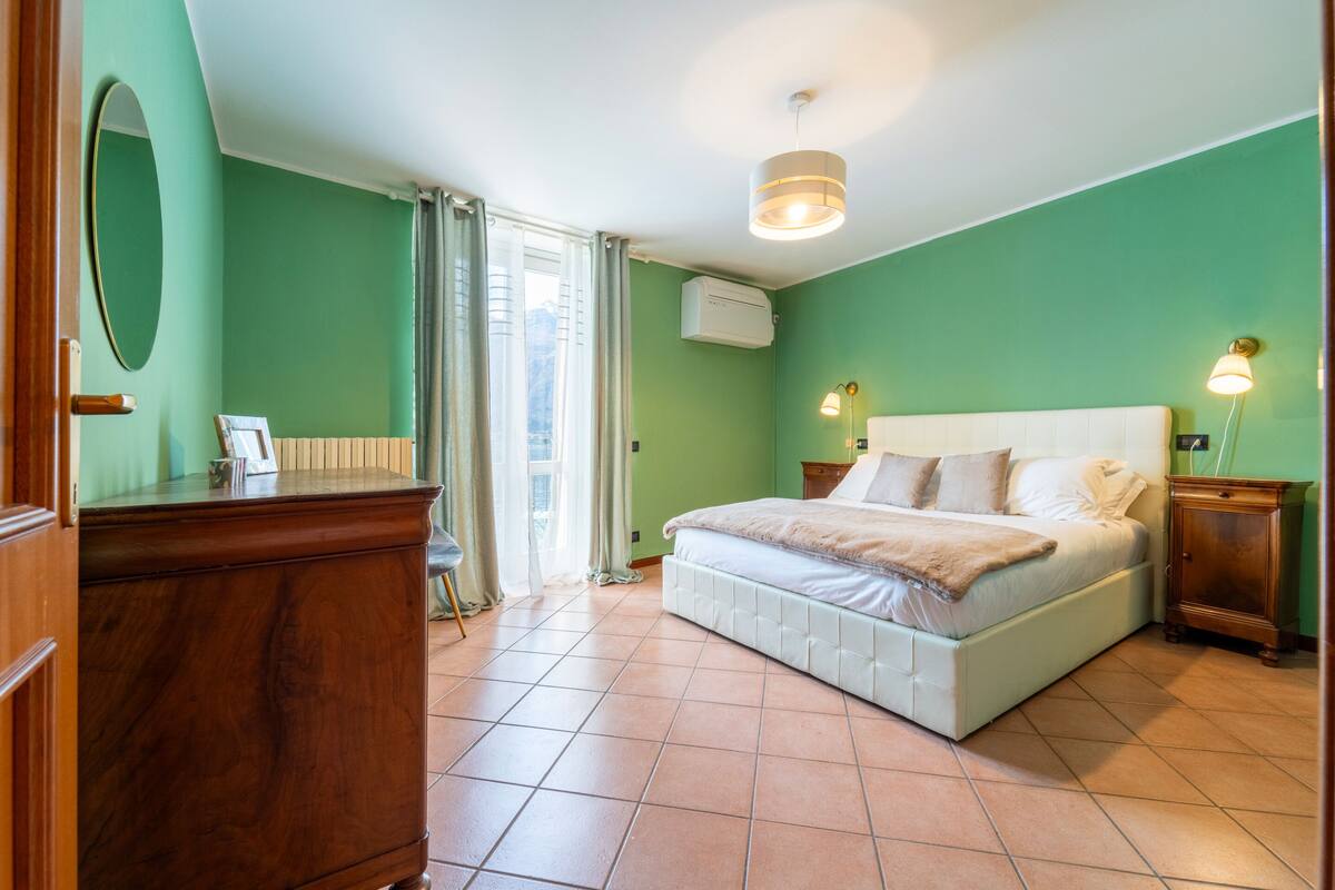 Une chambre à coucher avec un grand lit, une commode, un miroir et un luminaire au plafond.