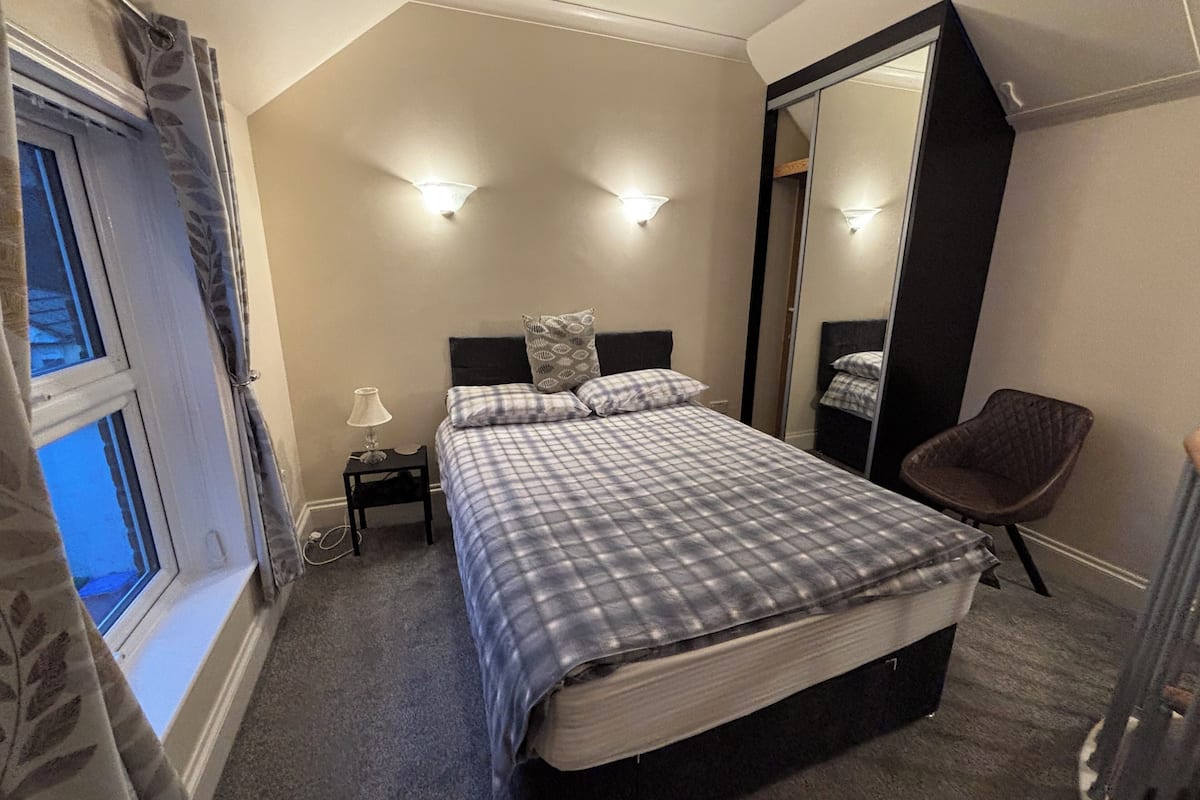A bedroom with a bed, bedside lamp, and a chair.