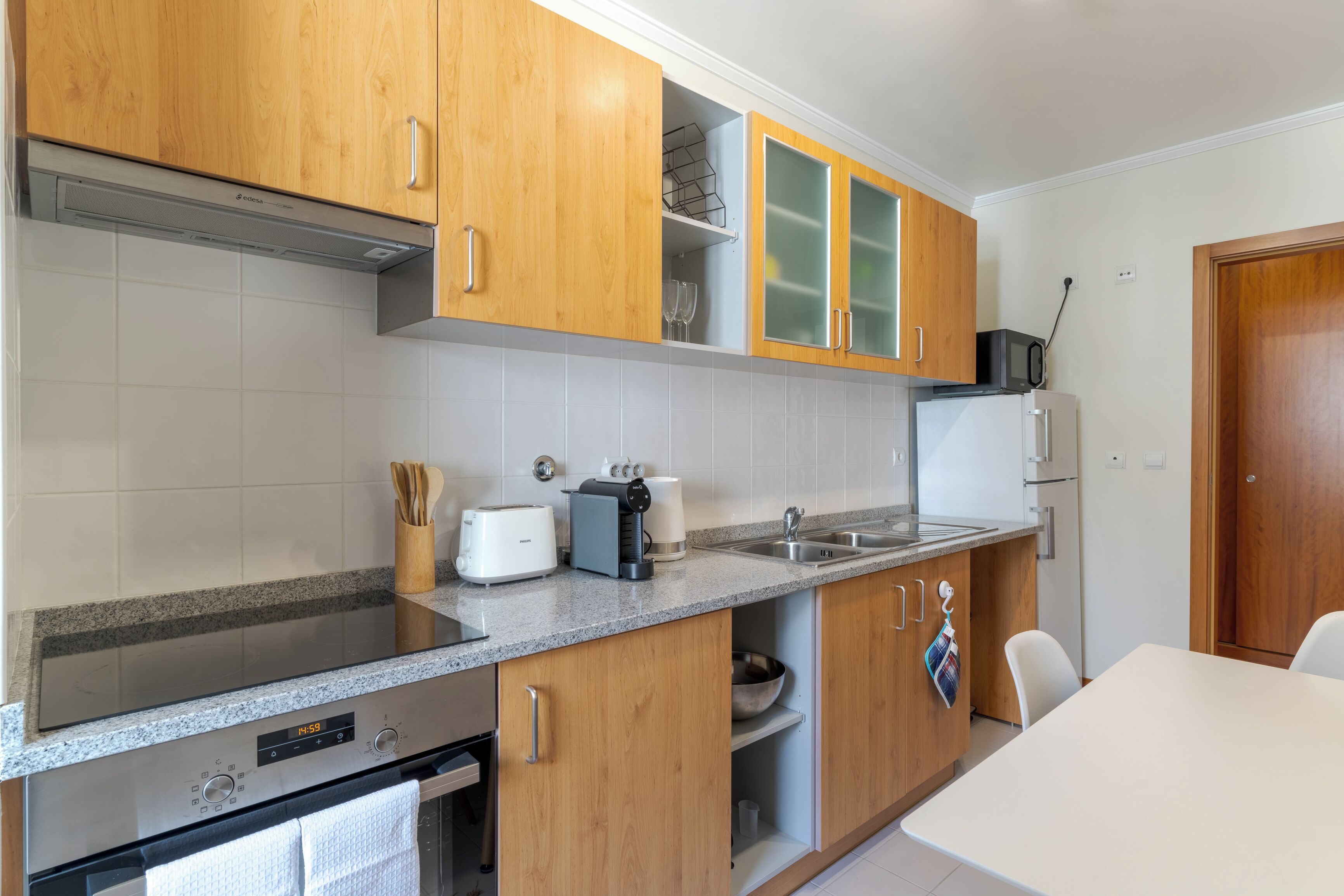 A modern kitchen with wooden cabinets, a built-in oven, a microwave, and a refrigerator.