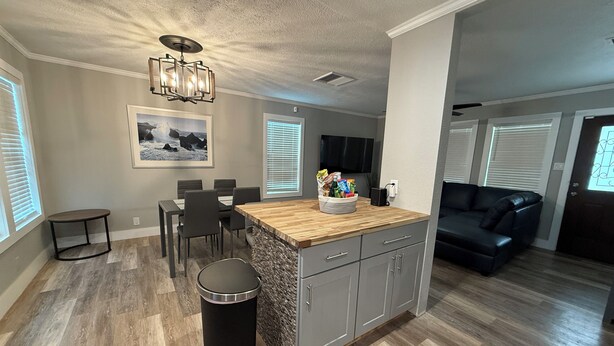A modern kitchen with a wooden island, dining area, and a living room with a sofa.