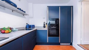 A compact kitchen with blue cabinets, a built-in oven, and a microwave.