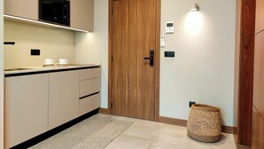 A modern kitchen with a built-in microwave, a wooden door, and a small basket. - King Studio 3 (Leiria)
