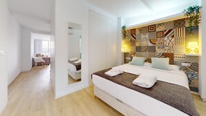 A modern hotel room with a large bed, a desk, and a view of the sea.