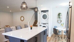 A modern kitchen with a central island, built-in appliances, and a dining area with a table and chairs.