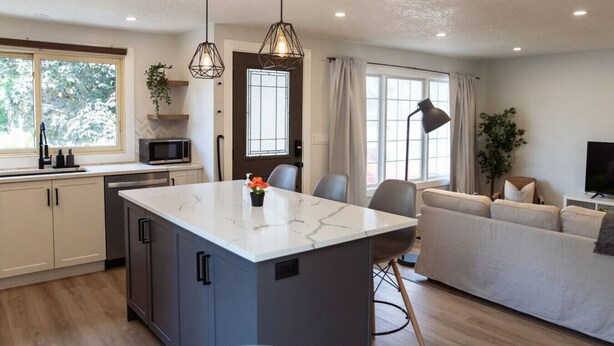 A modern kitchen with a central island, a dining area with a sofa, and a living room with a TV.
