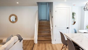 A modern kitchen with a wooden staircase leading to a dining area.