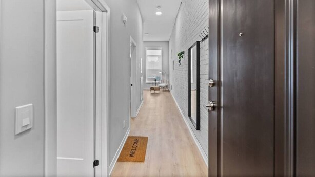 Un couloir aux murs blancs, doté d’un plancher en bois et agrémenté d’un paillasson.