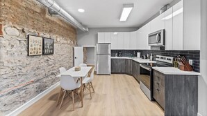 A modern kitchen with white cabinets, a black backsplash, and a stone wall. - Stylish Loft Downtown w/ Views + Near River/Trails (Peterborough)