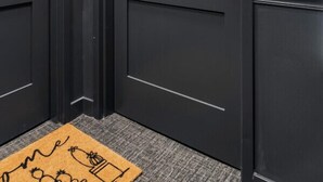 A hallway with two dark wooden doors, a doormat with a drawing, and a sign indicating room G10. - 1Bedroom | Downtown | Gym & Coworking space + Wifi (Cincinnati)