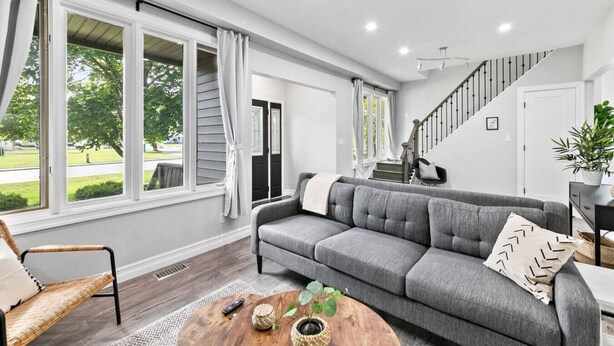 A spacious living room with a grey sofa, a wooden coffee table, and a staircase leading to an upper level.