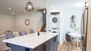 A modern kitchen with a central island, built-in appliances, and a dining area with a round table and chairs. - 5Bd/2Ba Luxe Family Home - WIFI, Parking (Kitchener)