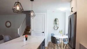 A modern kitchen with a marble countertop, a built-in refrigerator, and a dining area with a round table and chairs. - 5Bd/2Ba Luxe Family Home - WIFI, Parking (Kitchener)