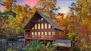 Une cabane en rondins dotée d’un balcon, entourée du feuillage automnal.