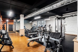 A gym with various exercise equipment, including treadmills, weight machines, and dumbbells.