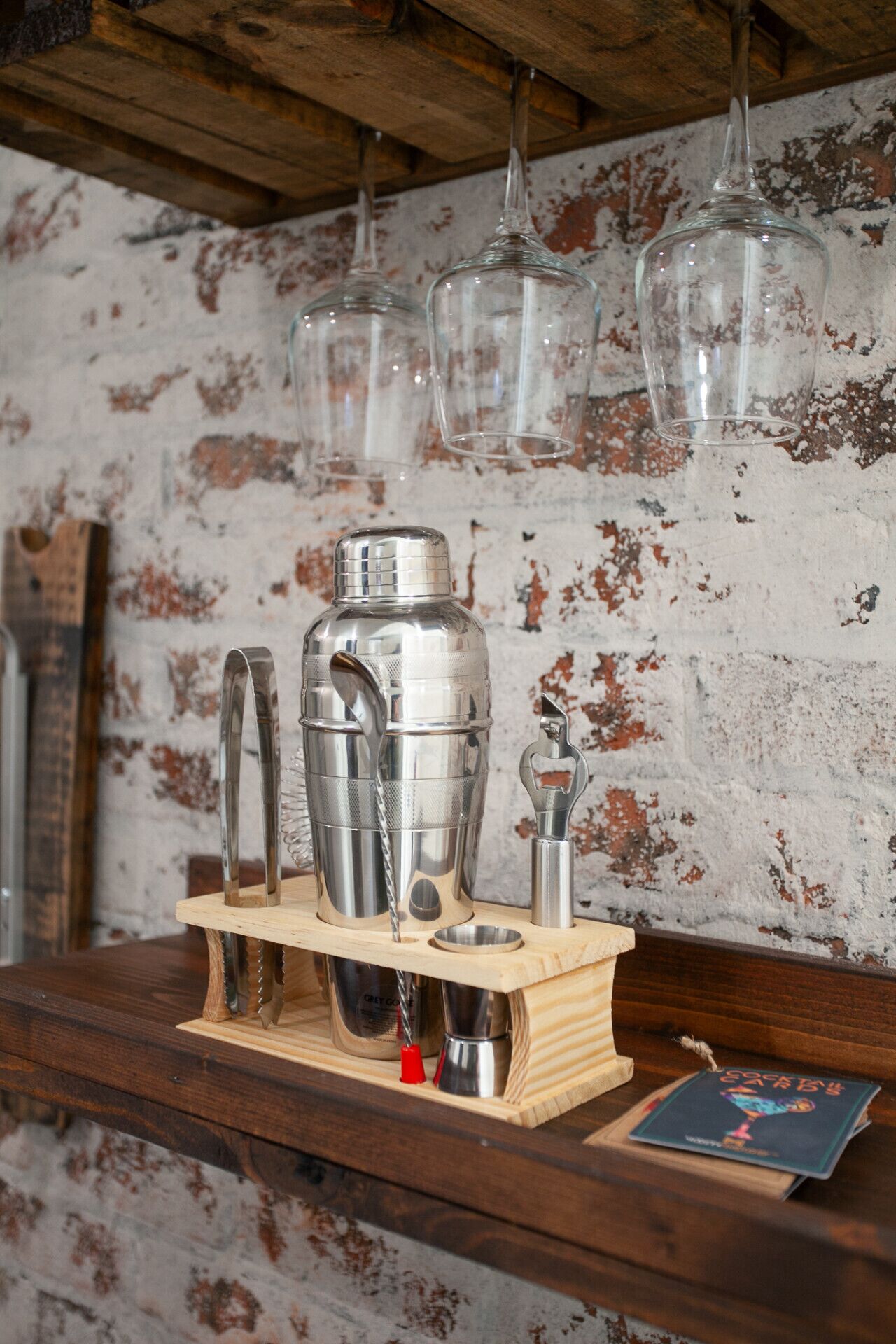 Un bar équipé d’un comptoir en bois, d’un ensemble de matériel pour préparer des cocktails et d’un menu.