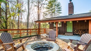 A wooden deck with Adirondack chairs, a fire pit, and a building with a green door and a chimney. - Peaceful Heights with Cozy Decks and Smart TV! (Townsend)