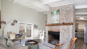 A living room with a fireplace, a dining area, and a kitchen. - Peaceful Heights with Cozy Decks and Smart TV! (Townsend)