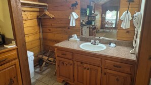 A wooden cabin bathroom with a sink, mirror, and wooden cabinets.