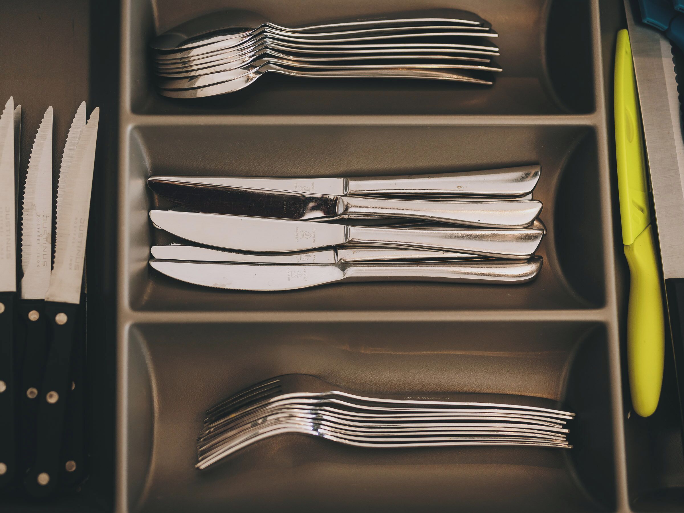 A drawer containing multiple sets of silverware, including forks, knives, and spoons, neatly arranged.