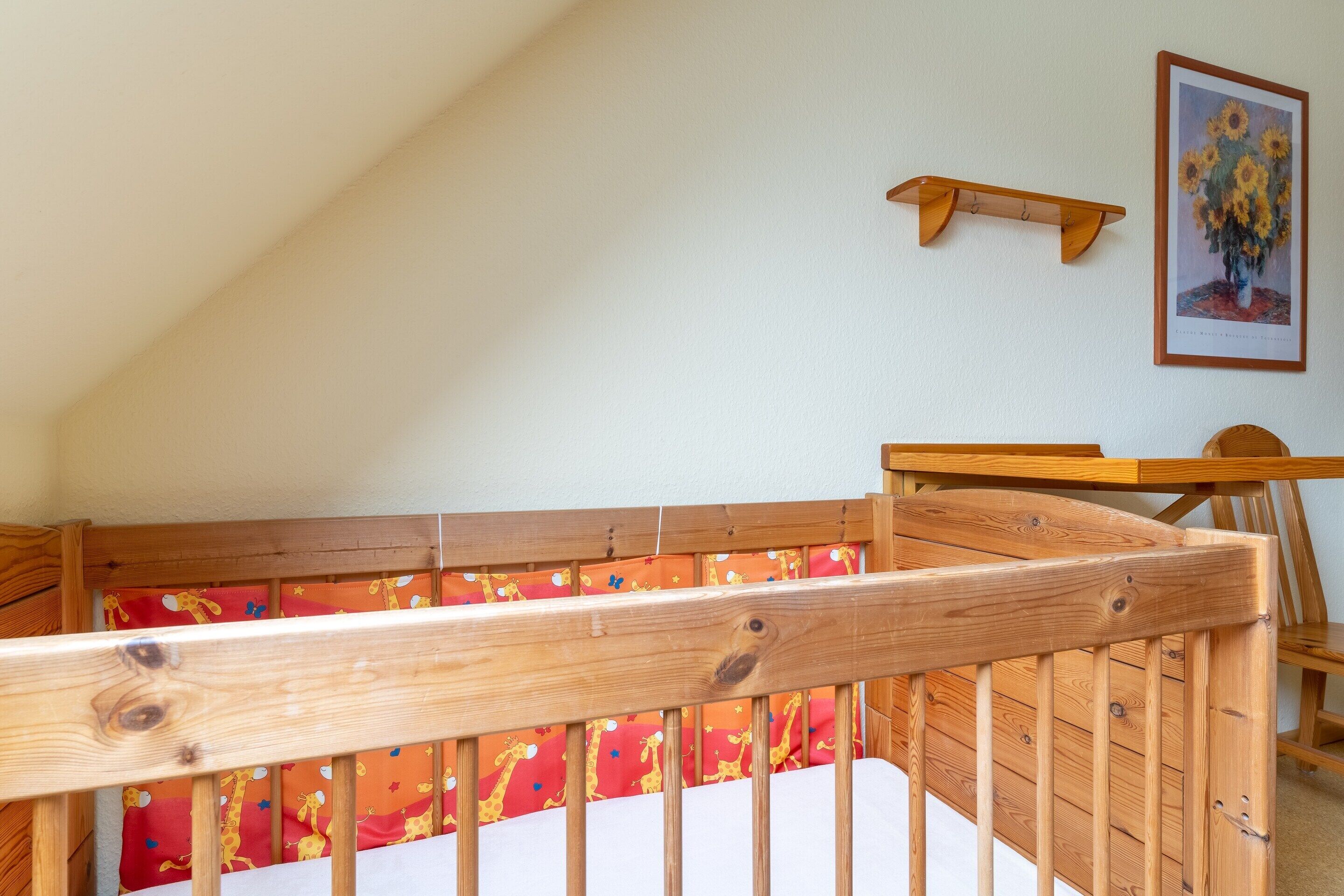 A wooden crib with a giraffe-patterned mattress in a room with a sloped ceiling.
