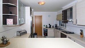 A modern kitchen with white cabinets, a stainless steel range hood, and a built-in oven. There is a coffee maker and a toaster on the countertop. - Apartment, Lagos - Formerly TUI Ferienhaus (Lagos)