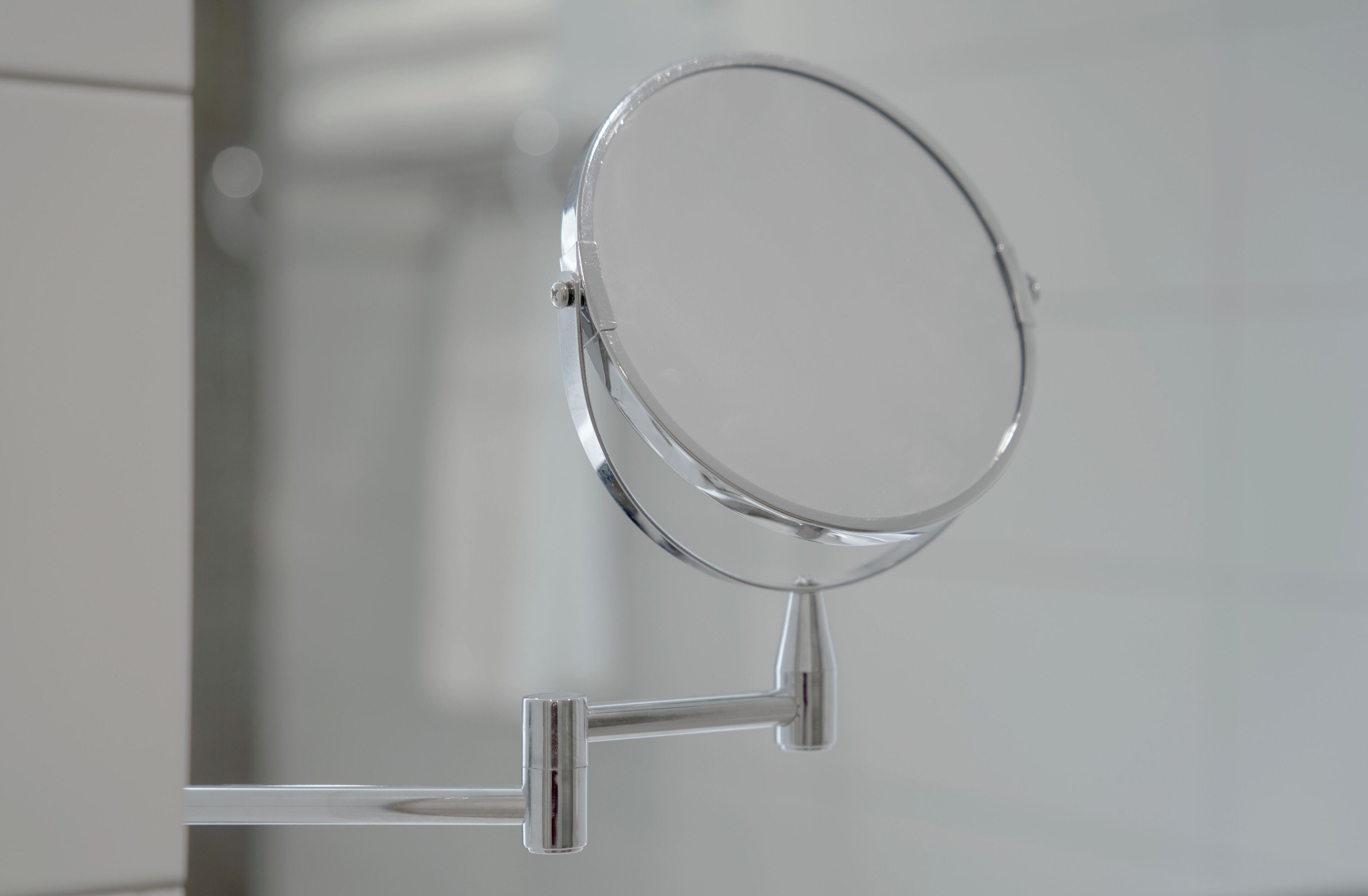 A bathroom mirror with a chrome finish and a simple, functional design.