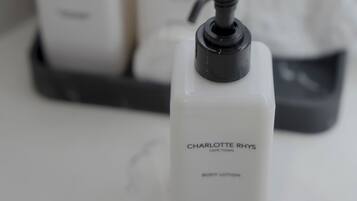 Un baño con tres botellas de loción corporal Charlotte Rhys y una toalla.
