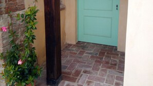 A brick pathway leading to a green door, with a potted plant on the left. - Agriturismo Cordiglianello  (Perugia)