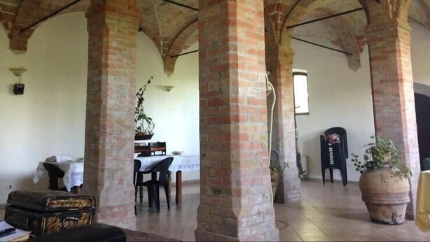 A spacious interior with high brick arches, a dining area with a table and chairs, and a large potted plant. - Agriturismo Cordiglianello  (Perugia)