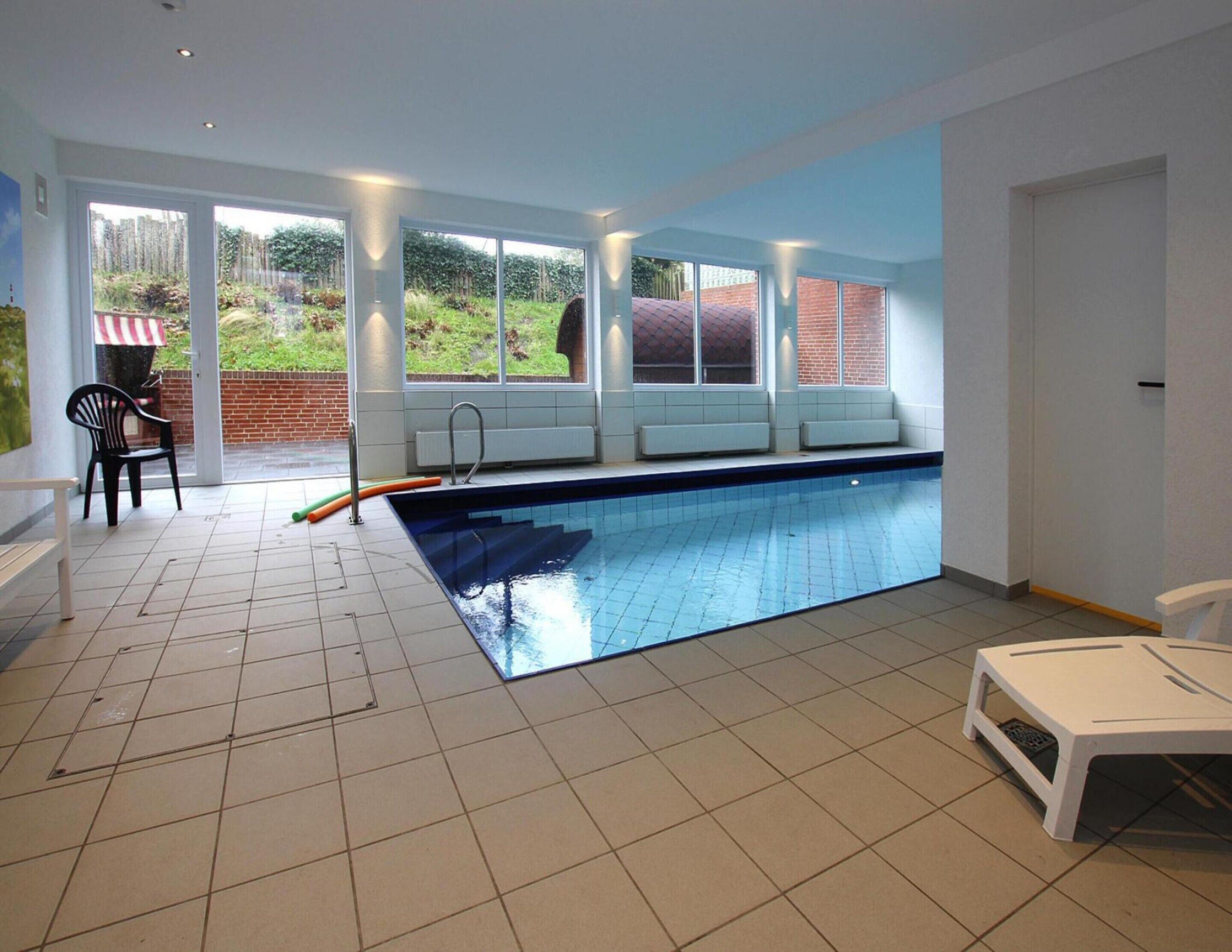 Une piscine donnant sur un jardin, avec de grandes fenêtres.