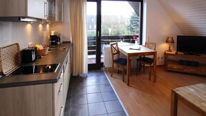 Una cucina compatta con zona pranzo e televisione.