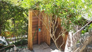 A wooden structure with a door, surrounded by greenery and rocks. - Apartment in Pegomas With Private Pool (Pegomas)
