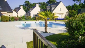 A residential area with a swimming pool, houses with sloped roofs, and a wooden fence. - Holiday Home in Erquy Near Sandy Beaches (Erquy)