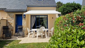 A house with a stone exterior, a tiled patio, a barbecue area, and a covered outdoor seating area with white chairs and a table. - Holiday Home in Erquy Near Sandy Beaches (Erquy)